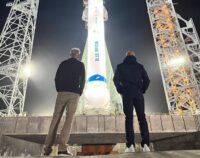 Two men looking at New Glenn rocket on pad